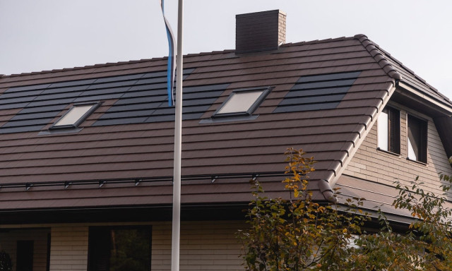 solar tiled roof of a house with a flag pole in front of it