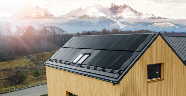 a house with a solar panel on the roof and mountains in the background