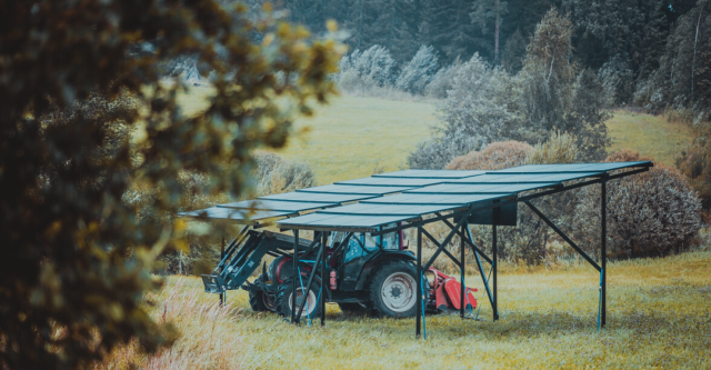 an image of solarstone solar carport with a tractor in a field with some trees
