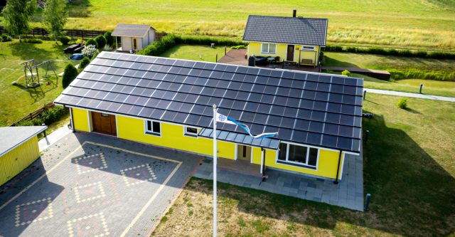 yellow building with solar full roof and a flag