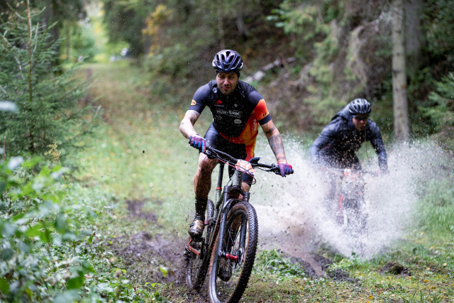 two electric bicycle riders going through the forest and the puddles