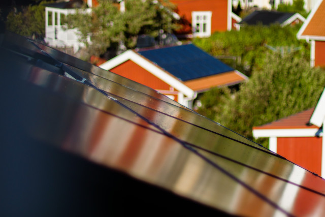 solar panels on the roof with red houses on the background