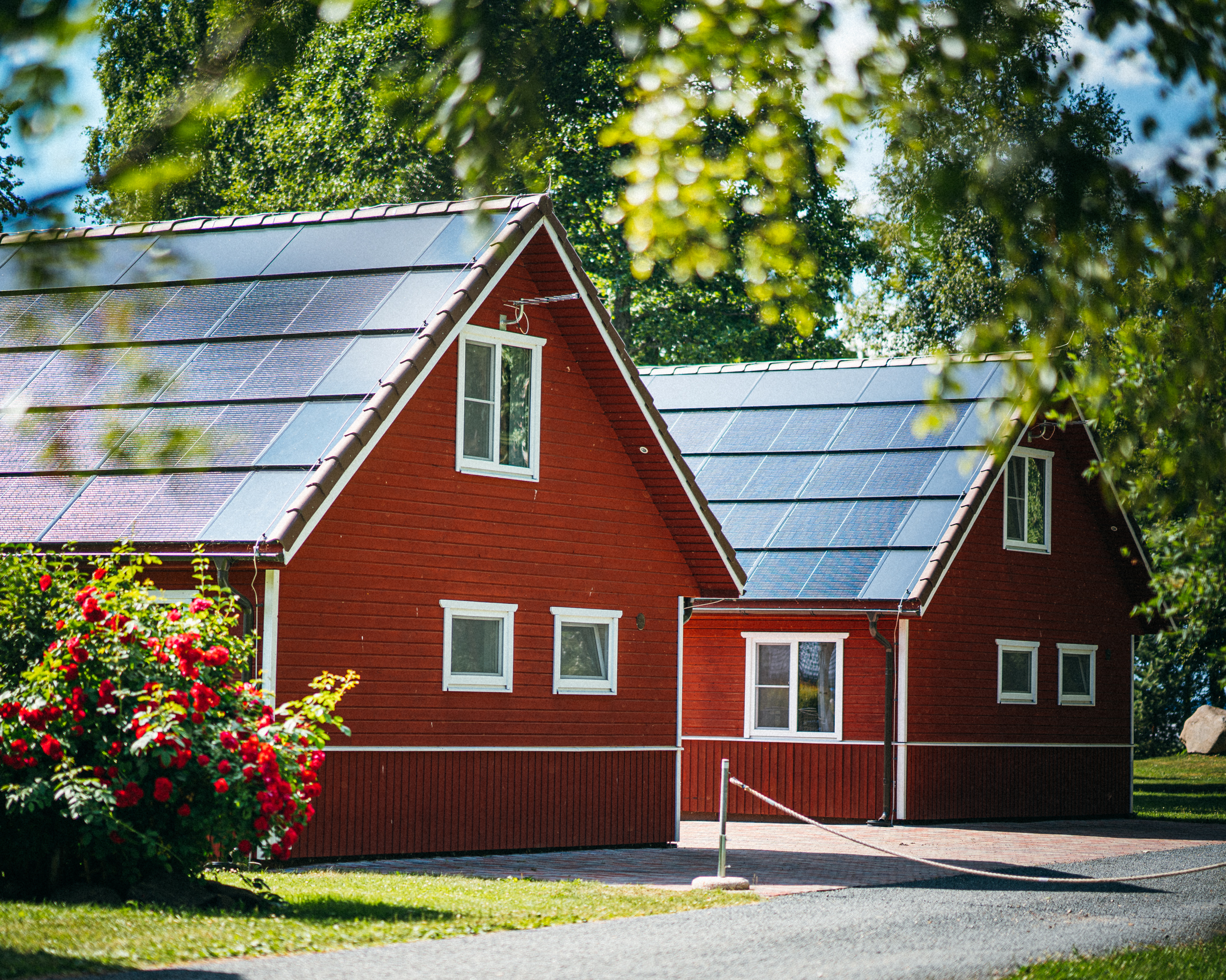 Röda hus med ett skinande Solarstone Solar Full Roof, som badar i sommarsolens ljus och visar upp sin eleganta design och miljövänliga integration.