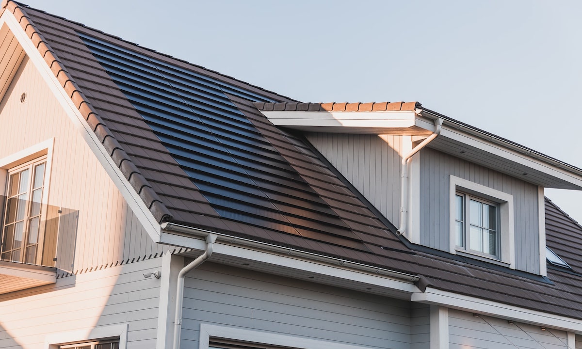 a gray house with a brown tiled roof and solar panels